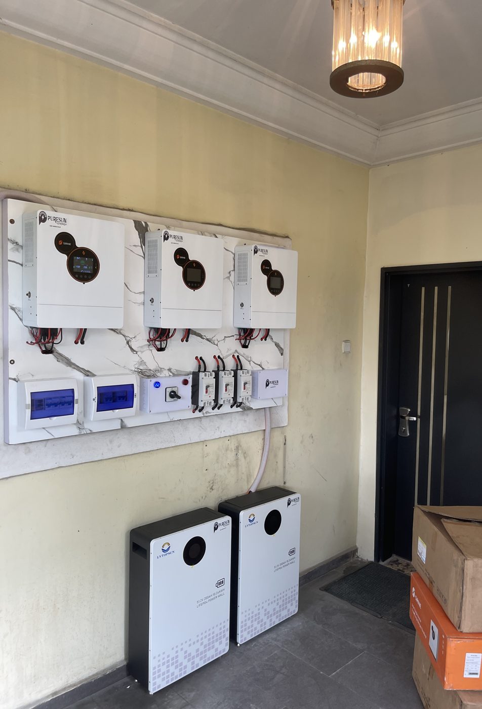 Three PureSun-branded inverters on a marble panel with two wall batteries below