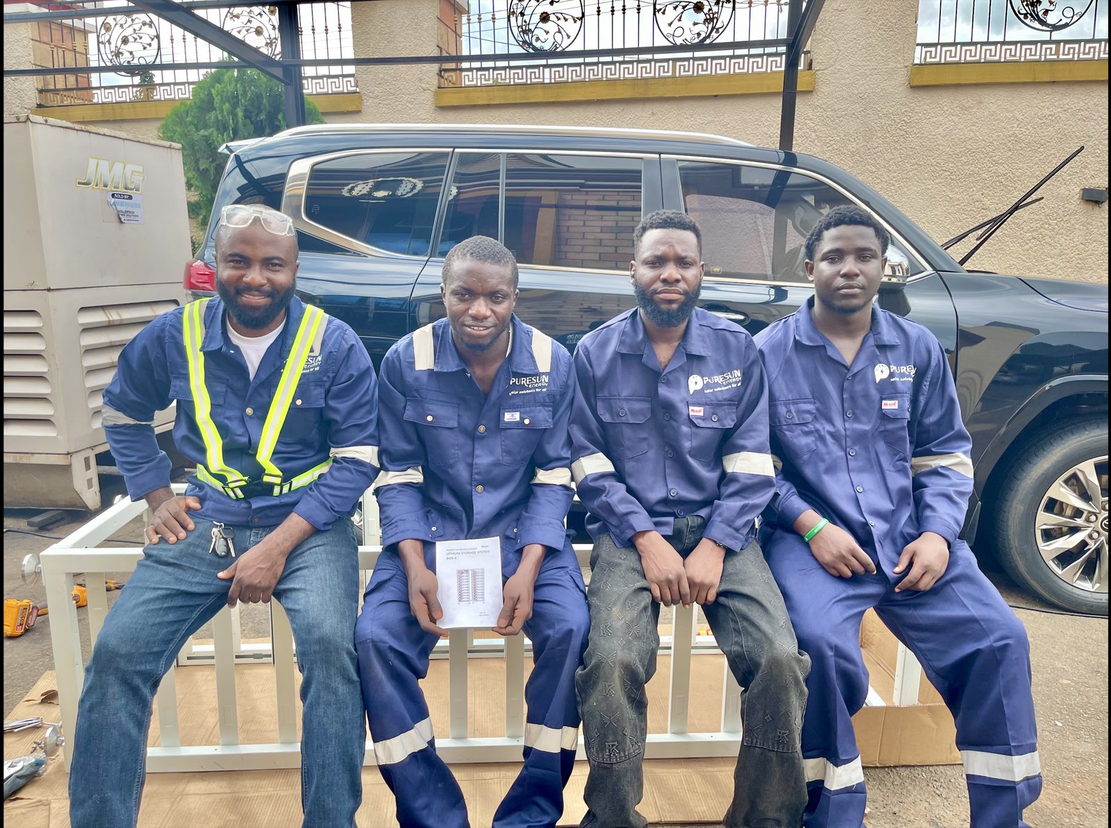 Four PureSun Energy technicians in blue branded overalls sitting side by side